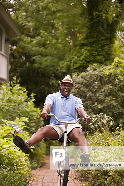 Afroamerikanischer Mann fährt Fahrrad im Hinterhof