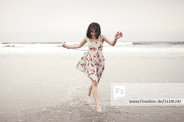 Caucasian woman running in waves on beach
