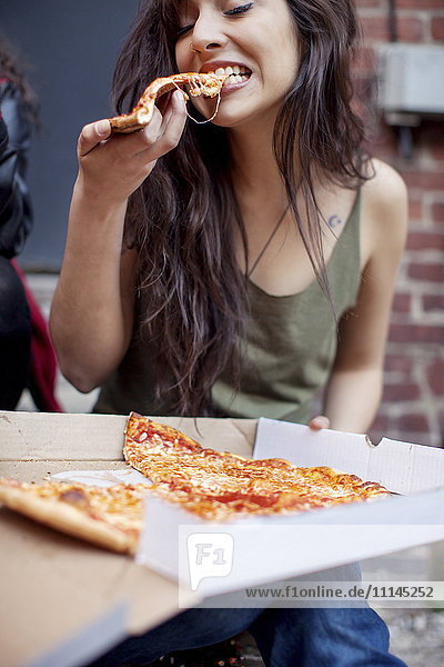 Mixed race woman eating pizza