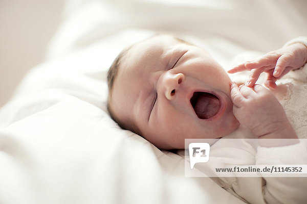 Caucasian baby girl yawning on bed