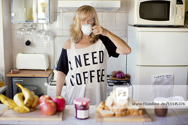Caucasian woman drinking coffee in kitchen