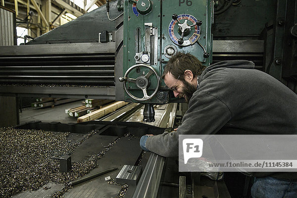 Caucasian man working at machinery in metal shop