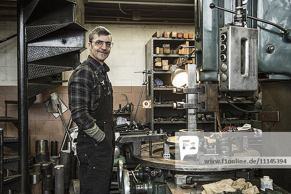 Porträt eines lächelnden kaukasischen Mannes in einer Metallwerkstatt
