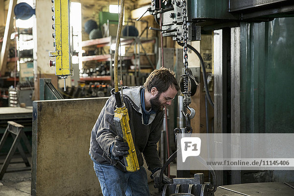 Caucasian man using machinery in metal shop