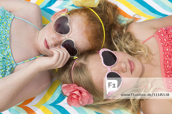 Kaukasische Mädchen beim Sonnenbaden mit herzförmigen Sonnenbrillen