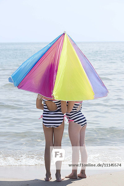 Kaukasische Mädchen unter Regenschirm am Strand