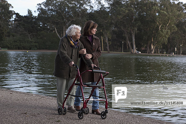 Frau geht mit Mutter am Teich spazieren