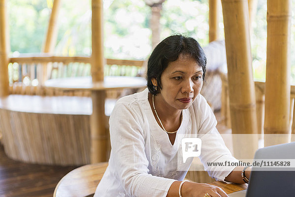 Balinese woman using laptop at table