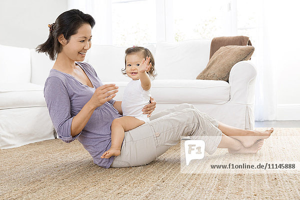 Mother playing with baby girl in living room