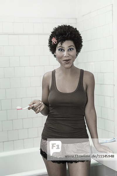 Frau putzt sich im Badezimmer die Zähne