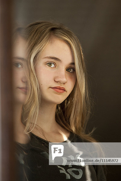 Ernstes Teenager-Mädchen  das sich im Spiegel betrachtet