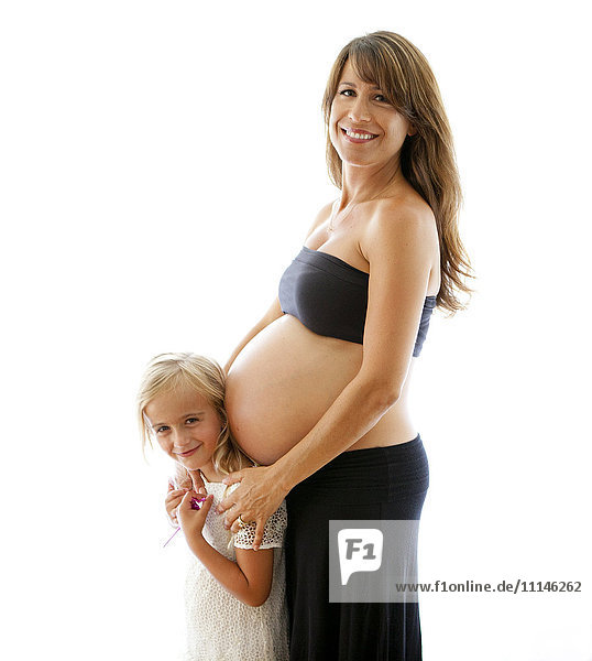 Lächelnde schwangere kaukasische Mutter  die ihre Tochter umarmt