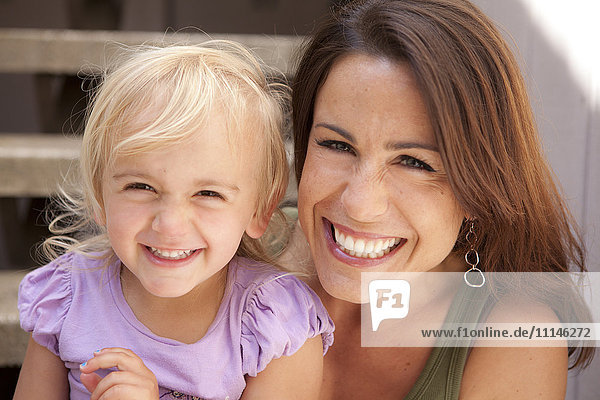 Caucasian mother and daughter smiling on steps