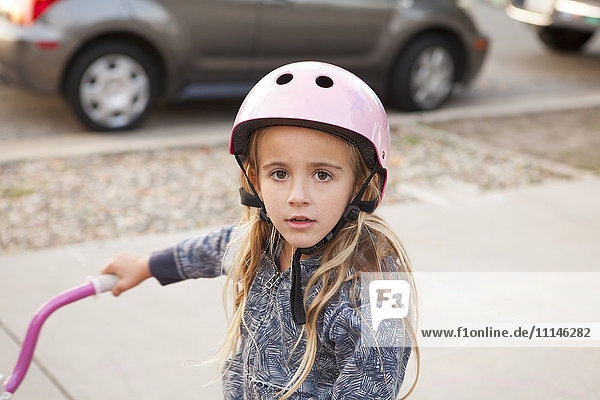 Kaukasisches Mädchen fährt Fahrrad auf dem Gehweg