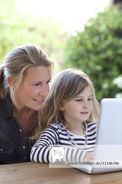 Mother and daughter using laptop at table