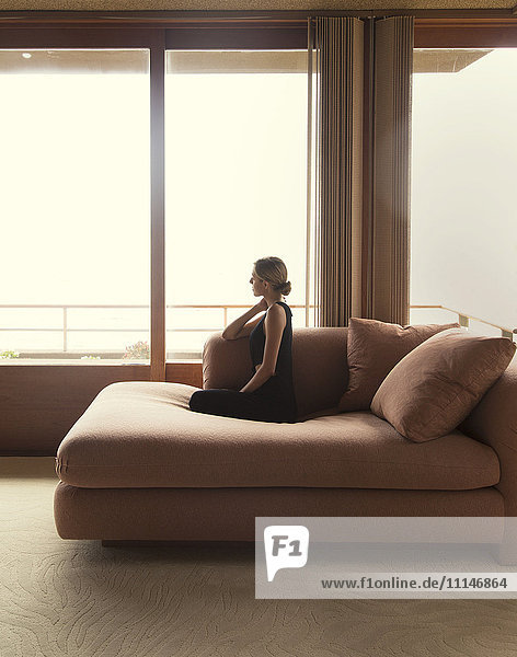 Frau sitzt auf Sofa in modernem Wohnzimmer