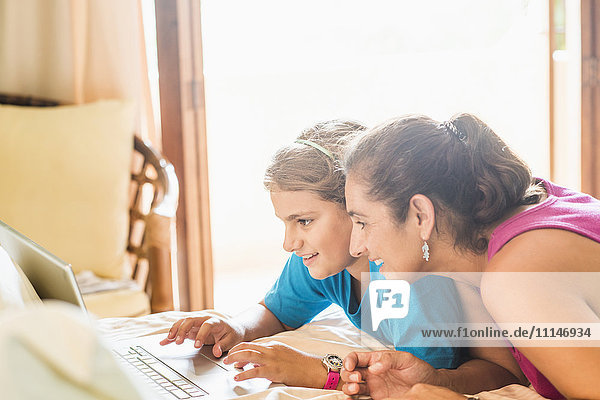 Mutter und Tochter benutzen Laptop am Schreibtisch