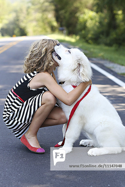 Nahaufnahme eines Mädchens  das einen Hund auf der Straße umarmt