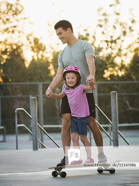 Father and daughter riding skateboard in park
