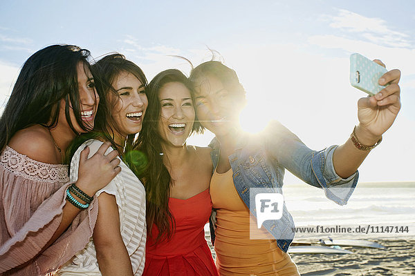 Women taking pictures together on beach