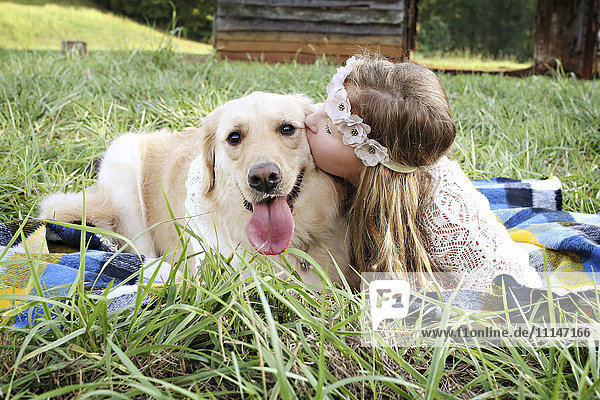 Kaukasisches Mädchen liegt mit Hund auf einer Decke
