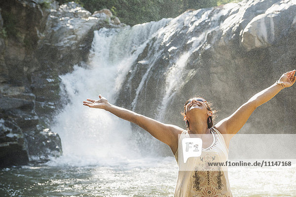 Hispanic woman standing by waterfall
