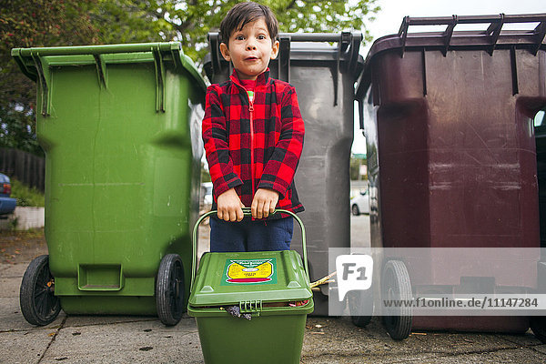 Mixed race boy carrying compost bin outdoors