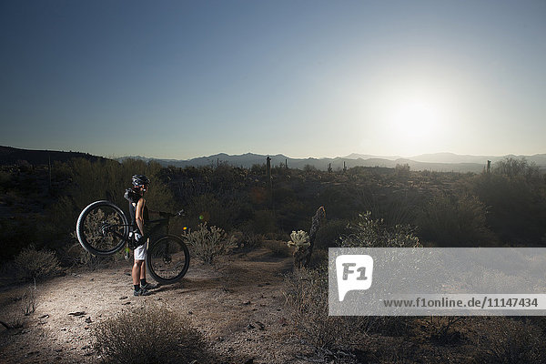 Mountainbiker in der Wüste stehend