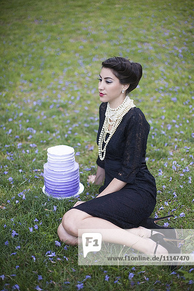 Frau sitzt mit Kuchen in einem ländlichen Feld