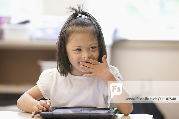 Gemischtrassiger Schüler mit Down-Syndrom benutzt Tablet-Computer im Klassenzimmer