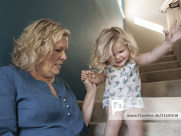 Großmutter hilft ihrer Enkelin beim Gehen auf der Treppe