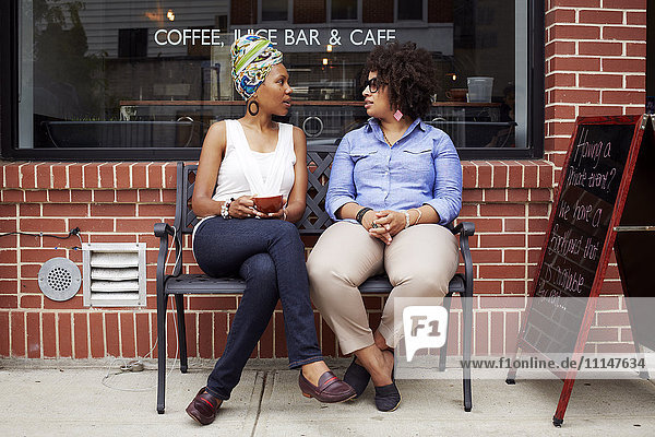 Women talking outside coffee shop on city street