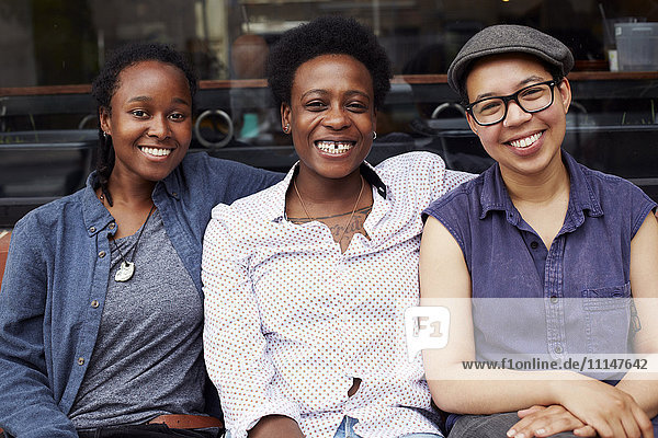 Lächelnde Frauen vor einem Café auf einer Straße in der Stadt