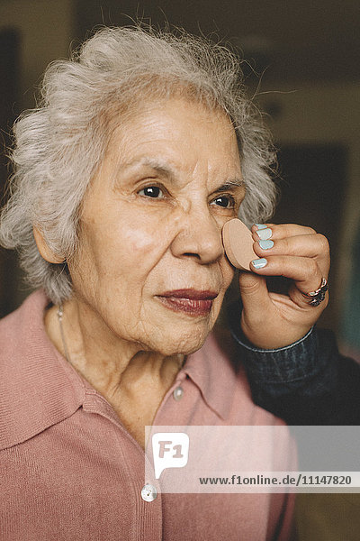 Enkelin trägt Make-up auf Großmutter auf