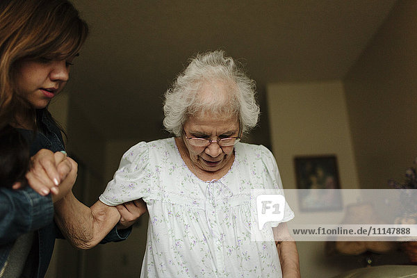 Enkelin hilft Großmutter beim Aufstehen