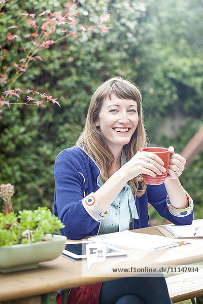 Gemischtrassige Geschäftsfrau trinkt Kaffee im Hinterhof