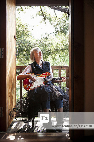 Kaukasische Frau spielt E-Gitarre auf Veranda