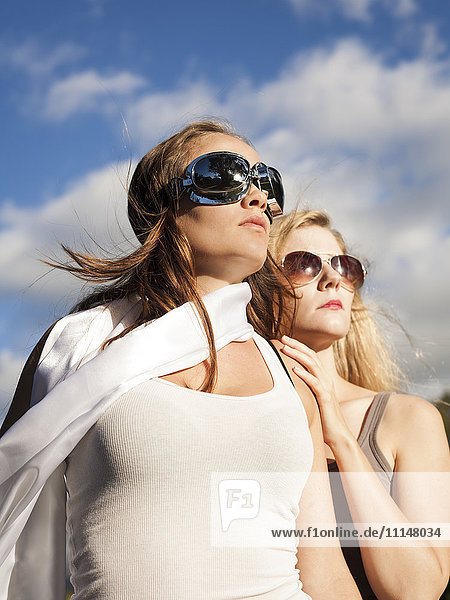 Caucasian women wearing sunglasses and looking up