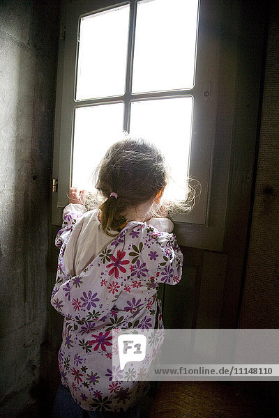 Caucasian girl looking out window