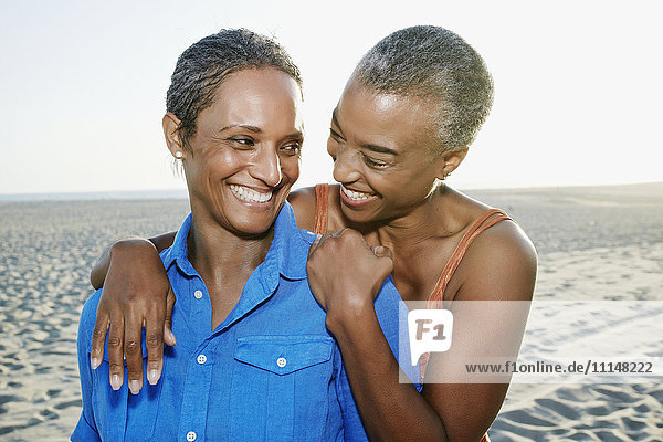 Ältere schwarze Frauen umarmen sich am Strand