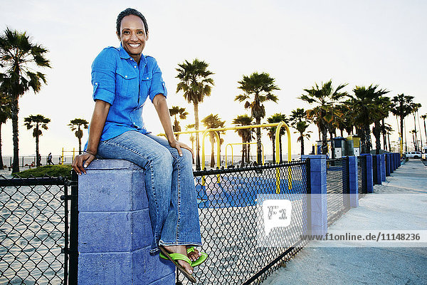 Older Black woman relaxing by park on beach