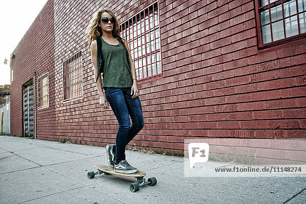 Gemischtrassige Frau fährt Skateboard auf einer Straße in der Stadt