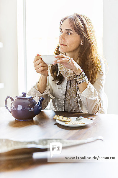 Kaukasische Frau trinkt Tee am Tisch