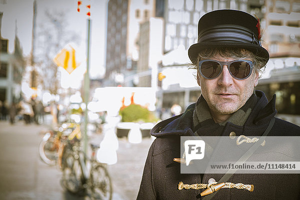 Kaukasischer Mann mit Zylinder auf dem Bürgersteig einer Stadt