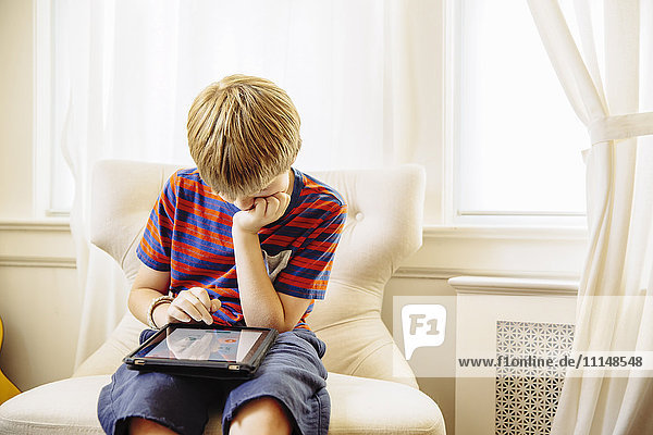 Kaukasischer Junge benutzt digitales Tablet im Wohnzimmer