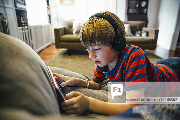 Caucasian boy using digital tablet on sofa