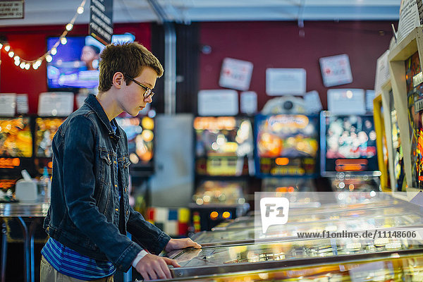 Caucasian teenage boy playing video game in arcade