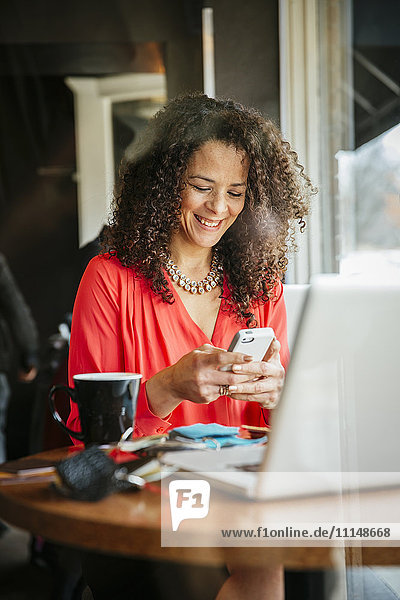 Businesswoman using cell phone in cafe