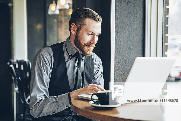 Caucasian businessman using laptop in cafe