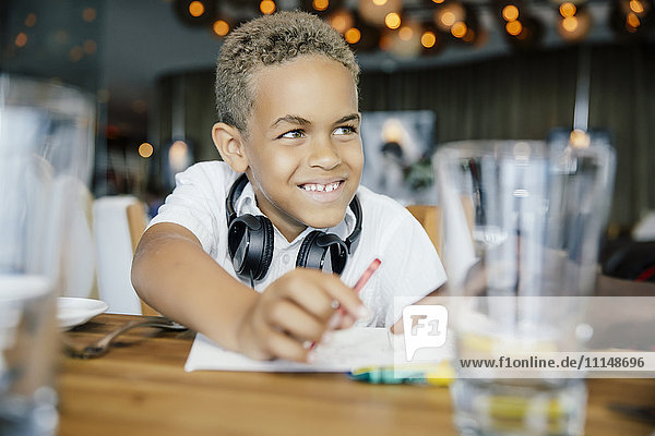 Mixed race boy coloring at restaurant table